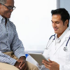 a doctor consults a chart while talking with a patient